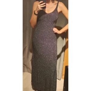 Glittrig långklänning - Snygg glittrig långklänning perfekt för festliga tillfällen. Klänningen har en tight passform och är ärmlös med smala axelband. Den glittriga ytan ger en lyxig känsla och gör den idealisk för nyår eller andra speciella kvällar. Ett måste för garderoben om du vill glänsa!
