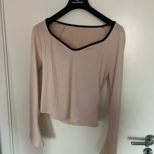 Beige ribbad topp från Zara - Säljer en snygg beige ribbad topp. Den har en v-ringad design med långa ärmar och en croppad passform. Perfekt för både vardag och fest! 🥳