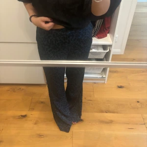 Leopard byxor i blått och svart - Säljer ett par snygga blå och svarta byxor med leopardmönster. De har en loose passform som ger en avslappnad stil. Perfekta för både vardag och fest! 🐆💙