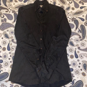 Mörkgrön skjorta från stenströms - Säljer en stilren mörkgrå skjorta från stenstöms i 100% bomull. Skjortan har långa ärmar och knappar framtill. Perfekt för både vardag och festliga tillfällen. Den är i mycket bra skick och redo för en ny ägare!