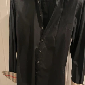Svart skjorta från Burberry - Fet skjorta skick 10/10 köpt för typ 3månader den har ba används fåtal gånger och perfekt till fest och vardag🥂🍾🍾🍾