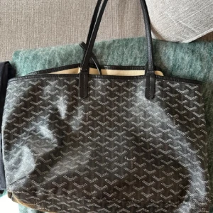 Svart mönstrad shoppingväska - Snygg svart shoppingväska med fint mönster. Väskan har två långa handtag och är perfekt för både vardag och shoppingturer. Den är rymlig och stilren, vilket gör den till ett måste i garderoben. Säljs pga ingen användning.