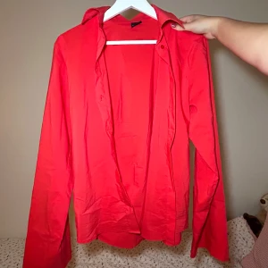 Röd skjorta från Gina Tricot - Säljer en snygg röd skjorta från Gina Tricot. Den har långa ärmar och en klassisk krage. Perfekt för både vardag och fest! Skjortan är i bra skick och passar till många olika outfits. 🔥Oversize och borttagna axelvaddar.