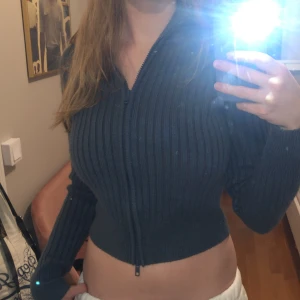 Gullig kofta  - En mörkblå cropped tröja med dragkedja. Har en krage. Använt ett fåtal ggr, bra kvalitet och inget slitage. Vet ej märket. 