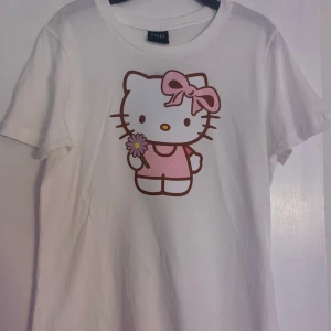 Hello Kitty t-shirt - Custommade av mig⭐️ Stl S men lite stor i storleken! Helt oanvänd T-shirt i 100% bomull. Skriv om du vill ha en med rhinestone text, kan göra custom baserat på önskemål🫶
