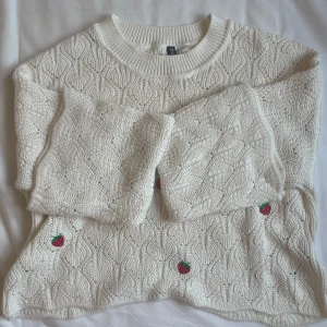 Vit stickad tröja med jordgubbsbroderi - Superfin vit stickad tröja från H&M med söta små jordgubbsbroderier. Den har en mysig och avslappnad passform med långa ärmar och ett fint mönster. Perfekt för både vår och höst! 😍❤️