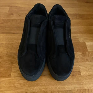 Arigato Clean 360 laceless i svart mocka.  - Lägger ut dessa igen pga oseriös köpare.                                                Axel Arigato Clean 360 laceless i svart mocka. Mycket bra skick. Kommer med box och dustbag. En liten defekt på tungan, se närbild. 