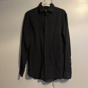 Svart skjorta med små prickar - Säljer en stilren svart skjorta från J.lindberg med små vita prickar. perfekt till vardagen eller när man ska vara lite uppklädd. Skick 7/10. frågor och funderingar? Tveka inte på att höra av dig