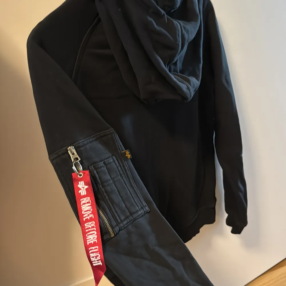 Svart hoodie från Alpha Industries. Fint skick. Storlek XS, passar nog också S. Hoodien har 2 fickor framme och 1 på vänster arm. Stor luva. . Hoodies.