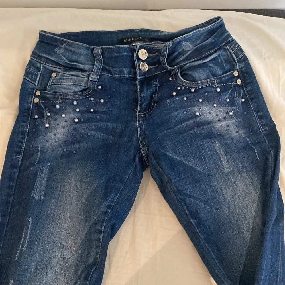 Säljer ett par snygga blå skin jeans från Mirelle i storlek 26 men passar tjej med Xs-S. De har coola pärldetaljer vid fickorna och en bekväm passform. Perfekta för både vardag och fest! 🥳. Jeans & Byxor.