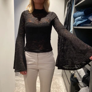 Svart spetsblus från Gina Tricot - Säljer en elegant svart spetsblus från Gina Tricot. Blusen har långa ärmar med vida ärmslut och en tight passform. Perfekt för festliga tillfällen eller en utekväll. Blusen är i nyskick och har en vacker spetsdesign som ger en sofistikerad look. 💛