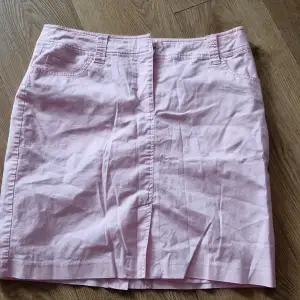 Säljer en söt rosa kjol från Joy i storlek 40. Kjolen är i en mjuk bomullsblandning med 1% elastan för lite stretch. Den har en klassisk design med fickor fram och bälteshällor. Perfekt för vår och sommar!