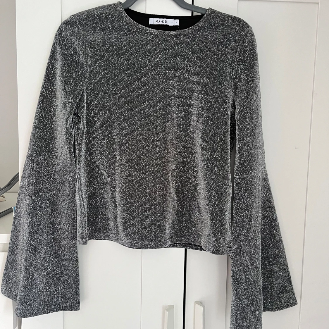 Glittrig topp med trumpetärm 