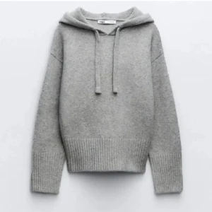 Grå stickad hoodie från Zara - Säljer en supermysig grå stickad hoodie från Zara. Den har en avslappnad passform med långa ärmar och en praktisk huva med dragsko. Perfekt för kyliga dagar när du vill vara både bekväm och stilren. Passar till både jeans och leggings!
