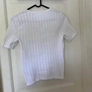 Vit stickad tröja från ONLY - Säljer en superfin vit stickad tröja från ONLY. Den har ett diskret mönster och korta ärmar, perfekt för vår och sommar. Tröjan är i fint skick och passar till de mesta. perfekt för både varda och fest