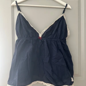 Mörkblå linne med spetsdetaljer från Odd Molly - Säljer detta jättesöta mörkblåa linnet från Odd Molly med fina spetsdetaljer längs kanterna. Den har smala axelband och en liten rosett framtill. Storlek 4, och skulle säga att den passar en large eller XL