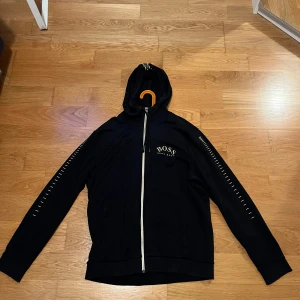 Hugo boss kofta - En jättefin guldsvart Hugo boss kofta som inte tillverkas längre. Koftan har kommit till användning men kan fortfarande användas sparsamt och diskret. Pris kan diskuteras vid snabbaffär 