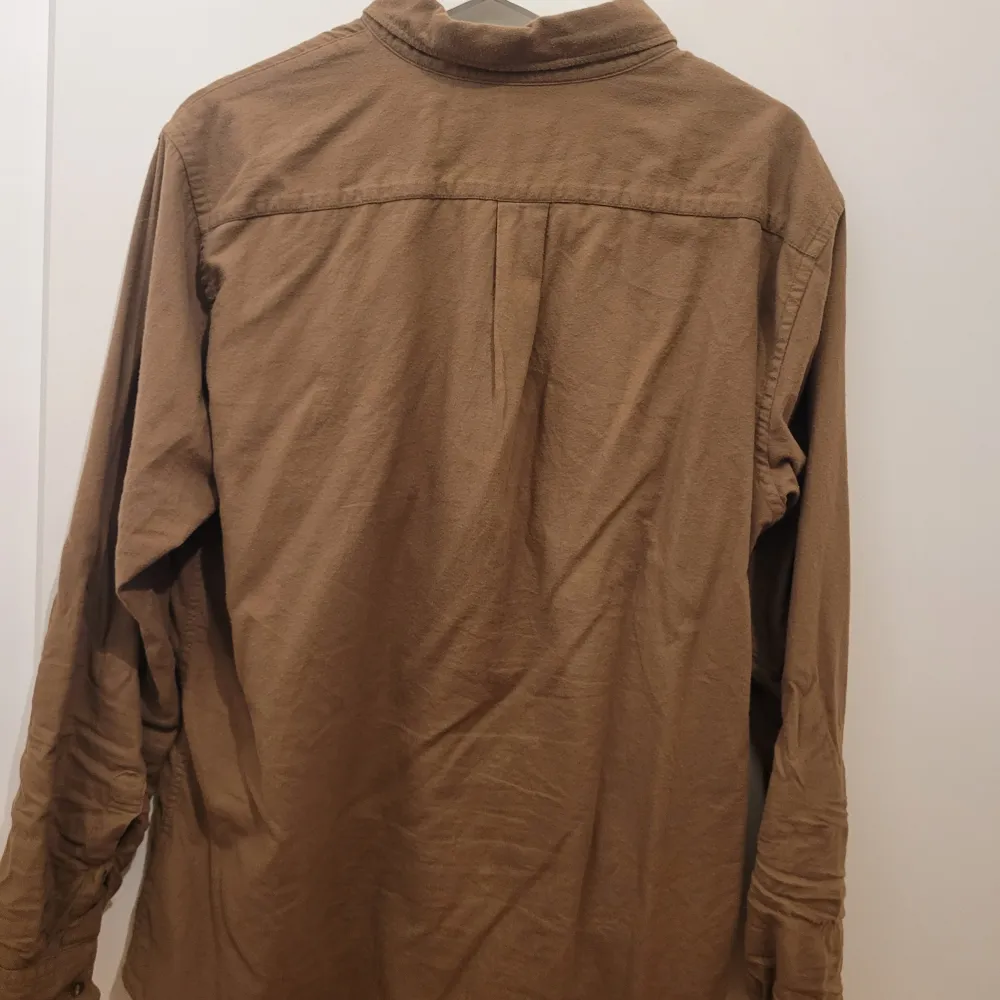 Säljer en snygg brun skjorta från Uniqlo i storlek M. Skjortan är långärmad och har en klassisk krage med knappar hela vägen ner. Perfekt för höst och vår, och funkar både till vardags och lite finare tillfällen. Den har en bröstficka som ger en extra touch. 🧡. Paidat.