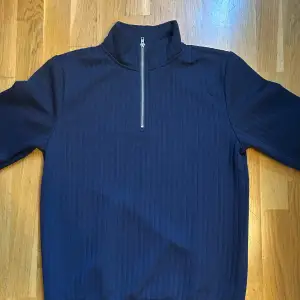 En marinblå tröja i storlek S med 1/4 zip