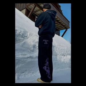 HCW Byxor  - varta jeans med lila sömmar och broderier. På baksidan finns ett broderat skelett och texten ”HEAVEN CAN WAIT”. På framsidan finns ett broderat kors med en dödskalle.   Heaven Can Wait  Oversized S storlek  Väldigt bra skick, använd ett par gånger!  