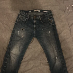 Replay Anbass - Säljer ett par riktigt snygga Replay Anbass Slim Fit i storleken 30, de är använda men i bra skick, liten defekt vid vänster ben. Nypris 1300 mitt pris 600