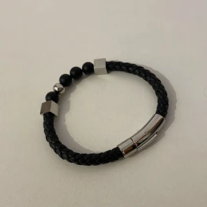 Läderarmband - Säljer ett läderarmband med stilrena detaljer! Armbandet passar till många kläder, färger och tillställningar. Det har en bra läsfunktion för lätt påtagning, pärlor och kuber som detaljer. Condition: 9/10. Tveka inte att höra av dig vid frågor!🤝😁💯