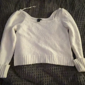 Vit stickad tröja - Säljer en superfin vit stickad tröja med puffiga ärmar. Den har en ribbad kant vid ärmslut och nederkant som ger en snygg passform. Perfekt för både höst och vinter, och den är i mycket bra skick. Passar till både vardag och fest!