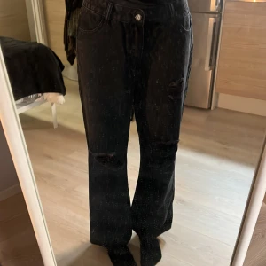 Svarta jeans med slitna detaljer från Shein - Säljer ett par svarta jeans från Shein i storlek L. De har en cool slitning över knäna som ger en edgy look. De är lite urtvättade därför kan några gråa streck synas på de, men inget som stör enligt mig! Säljer för att de är förstora i midjan! 