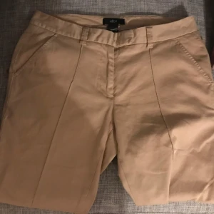 Beige byxor från Ellos - Säljer ett par snygga beige byxor från Ellos. De har en klassisk design med knappar och dragkedja framtill. Perfekta för sommardagar eller en avslappnad vårlook. Passar till både vardag och fest!  Aldrig använda. Storlek XL