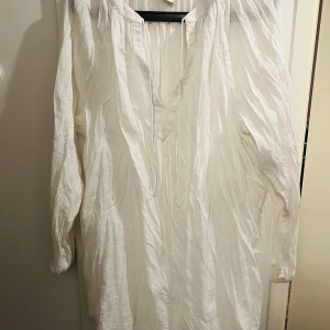 Vit långärmad blus från H&M - Säljer en superfin vit blus från H&M i storlek 46. Den har långa ärmar och en avslappnad passform med knytband vid halsen. Perfekt för både vardag och festliga tillfällen. Materialet är lätt och luftigt, vilket gör den idealisk för vår och sommar. 🕊️