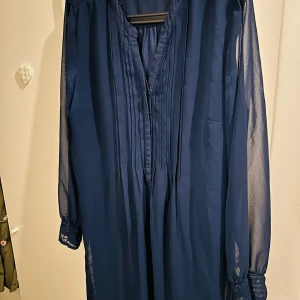 Mörkblå klänning från Isolde - Säljer en elegant mörkblå klänning från Isolde i storlek 42. Klänningen har långa ärmar med transparenta detaljer och en vacker plisserad framsida. Perfekt för höst- och vinterfester! 💙