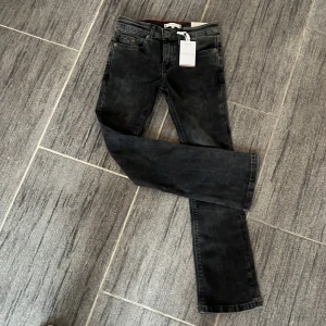 Mörk gråa/svarta jeans från Tommy Hilfiger - Säljer ett par snygga mörk gråa/svarta jeans från Tommy Hilfiger i storlek 140. De har en klassisk straight passform och är i mycket bra skick. Perfekta för både vardag och fest! 🖤