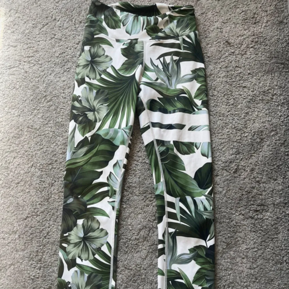 Snygga leggings med ett tropiskt blommönster i gröna nyanser. Perfekta för träning eller en avslappnad dag. De är stretchiga och bekväma med en hög midja som ger bra passform. Materialet är mjukt och andas, vilket gör dem idealiska för både inomhus och utomhusaktiviteter.. Sportswear.