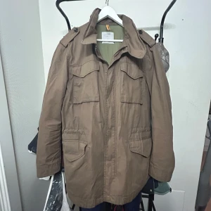 Peak performance Fält jacka  - Brun jacka från peakperformane, med utagbar luva. Cond 8/10 använd men ser inga slitage  