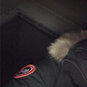 Svart parkajacka från Canada Goose - Säljer en svart parkajacka från Canada Goose med pälsdetaljer på huvan. Jackan är perfekt för kalla vinterdagar och har en snygg broderad logga på ärmen. Den är i bra skick och redo för nya äventyr. Passar perfekt för vinterns alla utomhusaktiviteter! ❄️