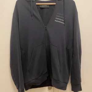 Mörkblå hoodie från Peak Performance - Säljer en snygg mörkblå hoodie från Peak Performance i storlek M. Den har dragkedja och en stilren design med loggan tryckt flera gånger på bröstet. Perfekt för både vardag och träning. Huvan är justerbar med snören och materialet är mjukt och bekvämt. Passar perfekt till höst och vår!