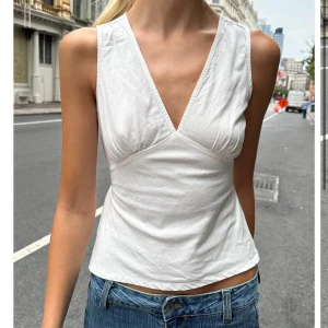 Vit brandy Melville topp - Säljer denna otroligt snygga toppen från brandy melville. Använd några gånger. Säljer då den inte kommer till användning längre. Skriv om ni har frågor🥰🥰