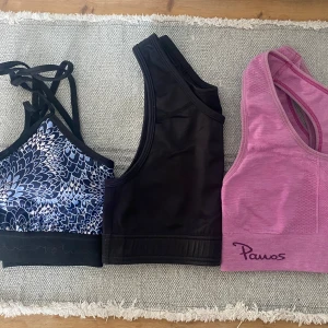 Tre sport-toppar från Panos mfl XS/S - Säljer tre sport-toppar från Panos mfl. En blåmönstrad med korsade axelband, en svart med breda axelband och en rosa ribbad topp. Perfekta för träning och aktiva dagar. XS/S.