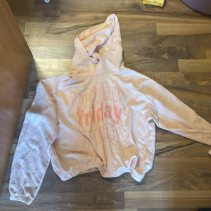 Rosa hoodie från H&M med text - Säljer en rosa hoodie från H&M med texten 'friday' tryckt i rosa och vitt på framsidan. Tröjan har en luva och långa ärmar, perfekt för en avslappnad stil. Passar bra till helgens chill.