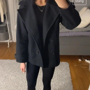 Marinblå kappa med knappar - Snygg marinblå kappa med dubbelknäppning och bred krage. Perfekt för kyligare dagar och ger en stilren look. Passar bra till både jeans och klänning. Är i storlek xs/s