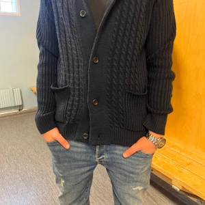 Mörkblå Cardigan  - Snygg mörkblå stickad kofta med knappar framtill och ribbade detaljer. Perfekt för kyligare dagar med sin långa ärmar och bekväma passform. Två praktiska fickor framtill. Pris kan diskuteras vid snabb affär.