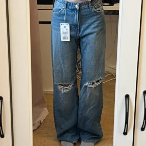 Ripped straight leg blå jeans - Snygga blå wide jeans med slitningar på knäna. Mellan hög midja och en rak modell som ger en avslappnad stil. Endast testade med prislapp kvar