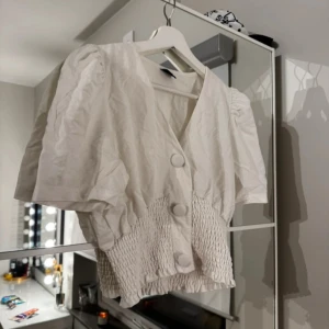 Vit fin topp  - Fin och stilren topp med knappar framtill, toppen formar och sätter sig fint efter kroppen!