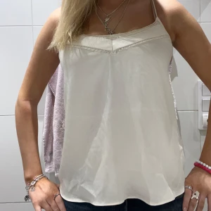 Vit ärmlös linnetopp - Snygg vit linnetopp med smala axelband och en enkel design. Perfekt för varma dagar eller som ett basplagg i garderoben.