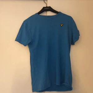 Blå t-shirt från Lyle & Scott - Snygg blå t-shirt från Lyle & Scott med korta ärmar och en liten broderad logga på bröstet. Perfekt för en avslappnad stil.