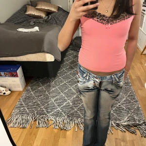 Rosa linne med spetsdetaljer - Snyggt rosa linne med svarta spetsdetaljer vid halsringningen. Perfekt för en somrig look eller en utekväll. Linnet har en tight passform och ärmlös design.