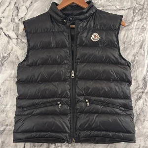 Svart dunväst från Moncler - Snygg svart dunväst från Moncler. bra skick bara att dragkedjan är lite sönder så lite svårt att dra upp men annars toppen för våren först till kvarn