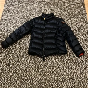 Mörkblå  dunjacka från Parajumpers - Snygg mörkblå dunjacka från Parajumpers med orange insida. Jackan är bara använd några få gånger och är som ny. Jackan är perfekt för den kalla kylan. Nypris ca 6000kr 