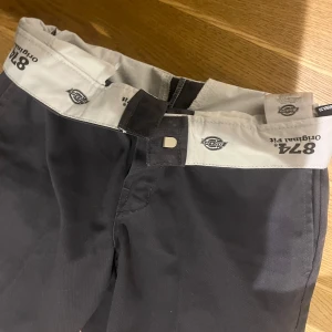 Slim fit Dickies  - Väldigt bekväma och stilrena byxor från Dickies.  Dom är mörkgrå och aldrig använda. Sitter som ett par kostymbyxor 💗 Passar både tjej och kille.  Midja 28 cm, Längd 30 cm. Ungefär storlek M skulle jag tippa på.