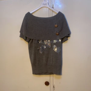 Säljer en grå tröja med en rosett (paljetter  - Super fin tröja med fina detaljer. Det står att storleken är L men passar XS-M